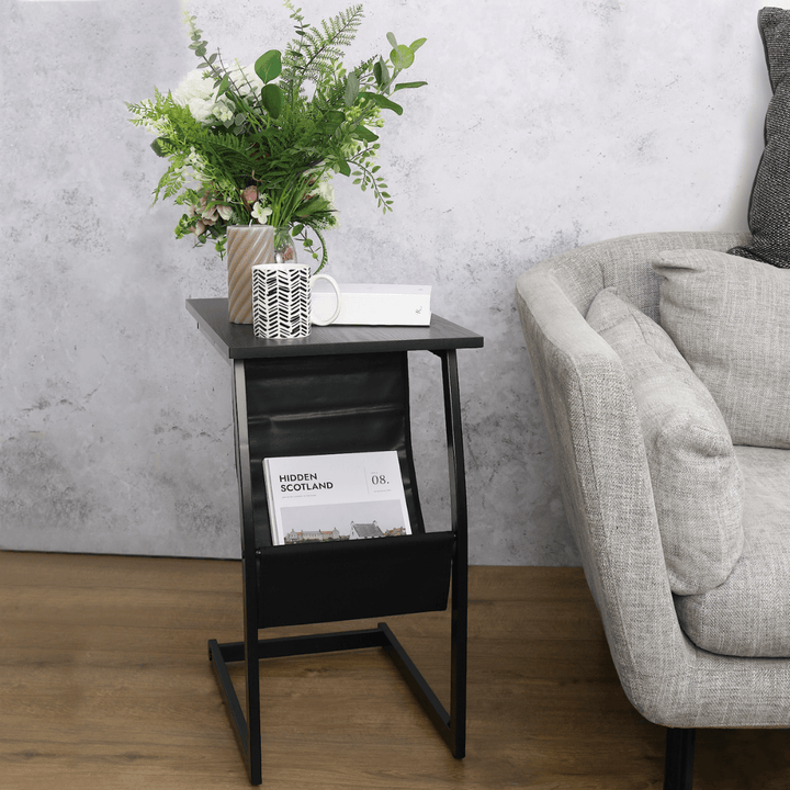 magazine rack side table styled beside sofa with coffee mug, candle and magazines