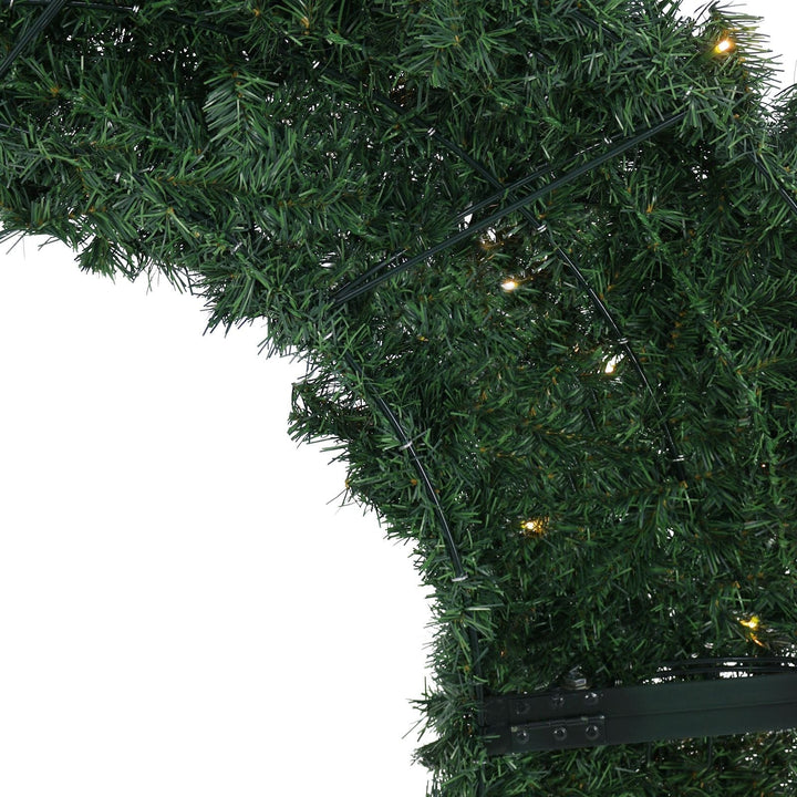 Close-up of a green artificial Christmas tree with lights on a white background