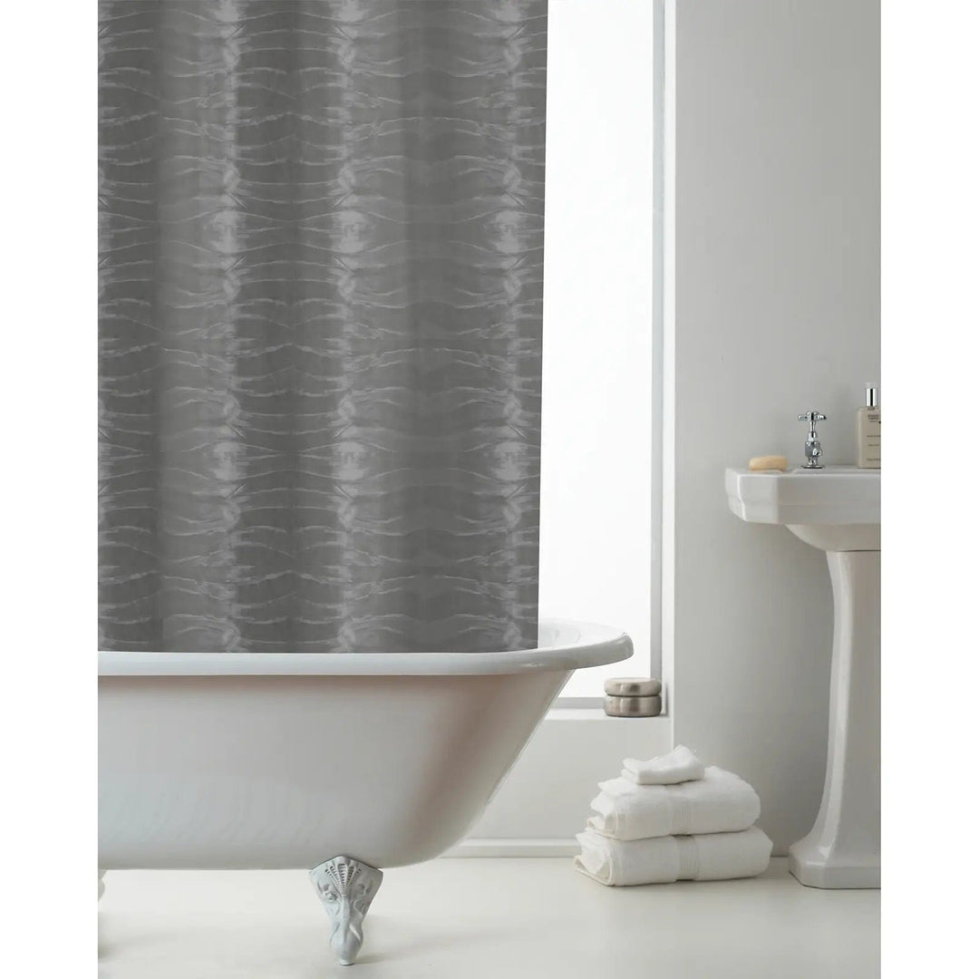 Smokey grey 3D waves pattern shower curtain hanging over a bath with white towels and sink