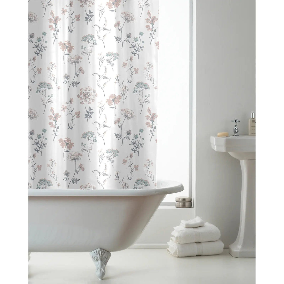 Pastel pink floral pattern shower curtain hanging in a bathroom with white towels