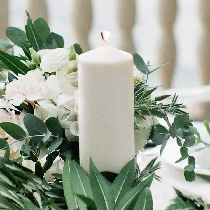 White pillar candle in a wedding table floral display