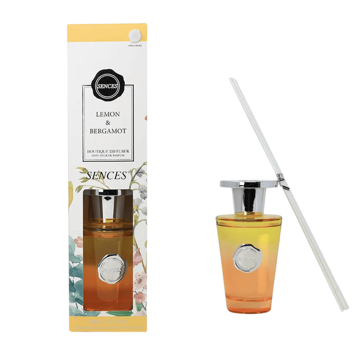 lemon and bergamot box packaging beside yellow and orange ombre glass bottle with white reeds