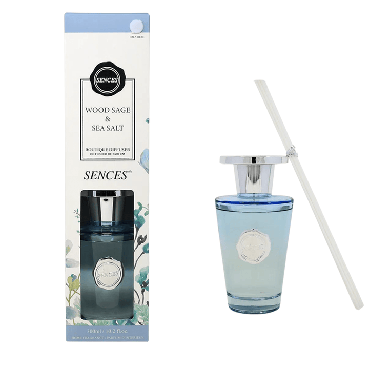 wood sage & sea salt diffuser box beside blue glass diffuser bottle with white reeds