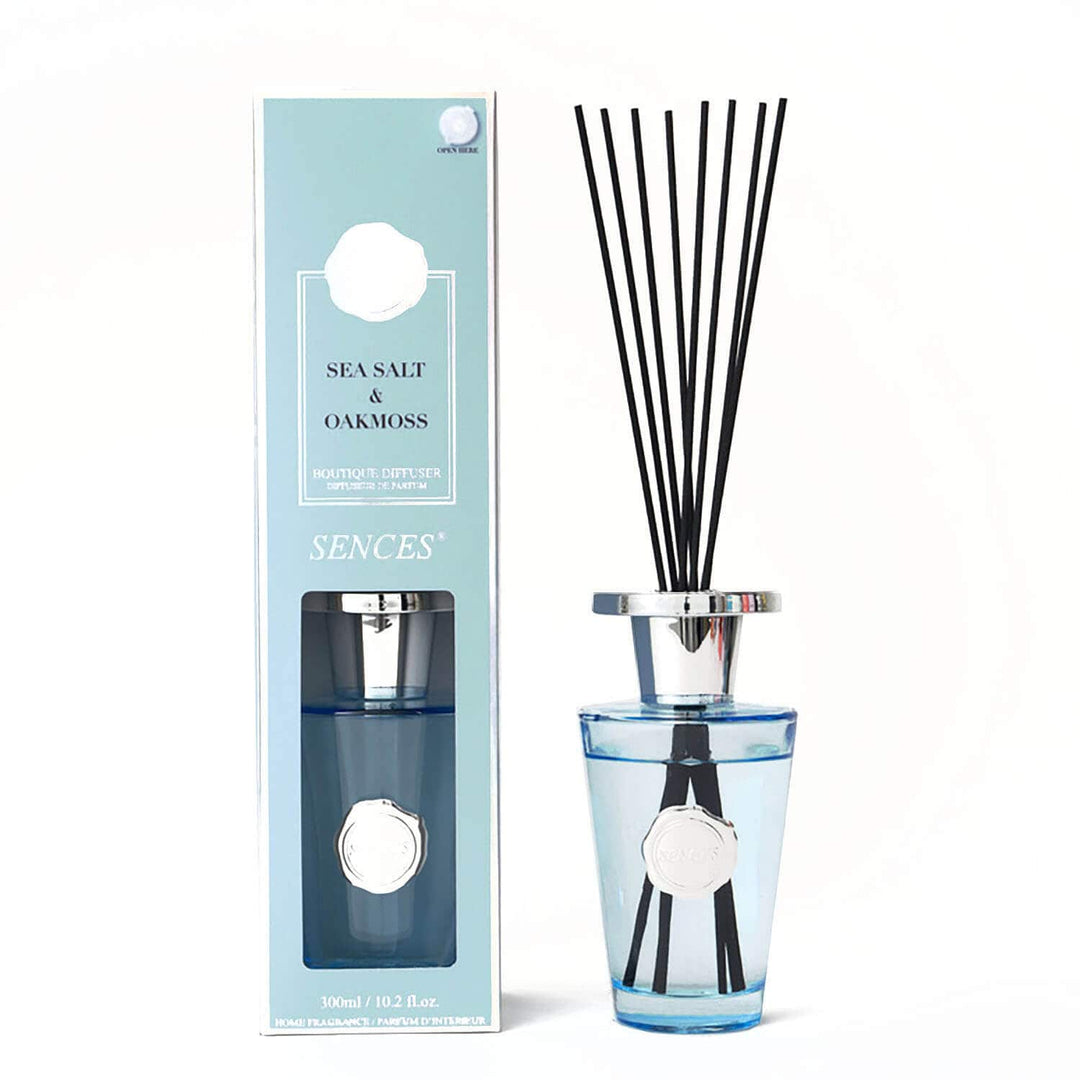 Sea sat and oakmoss scented reed diffuser bottle with black reeds and a light blue glass base stands next to its matching light blue box.