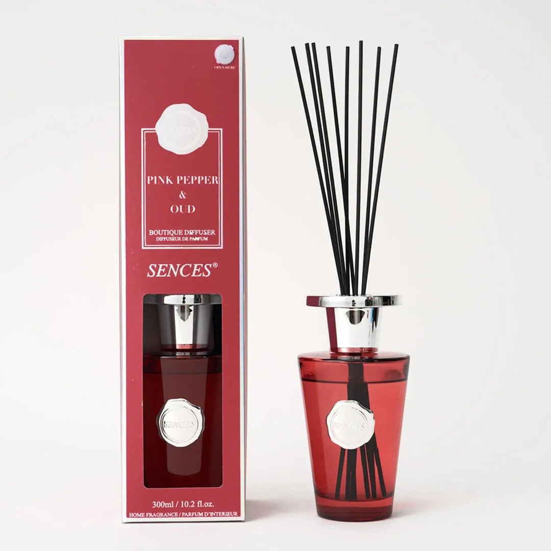 Pink pepper and oud scented diffuser in red packaging, silver top bottle with black reeds