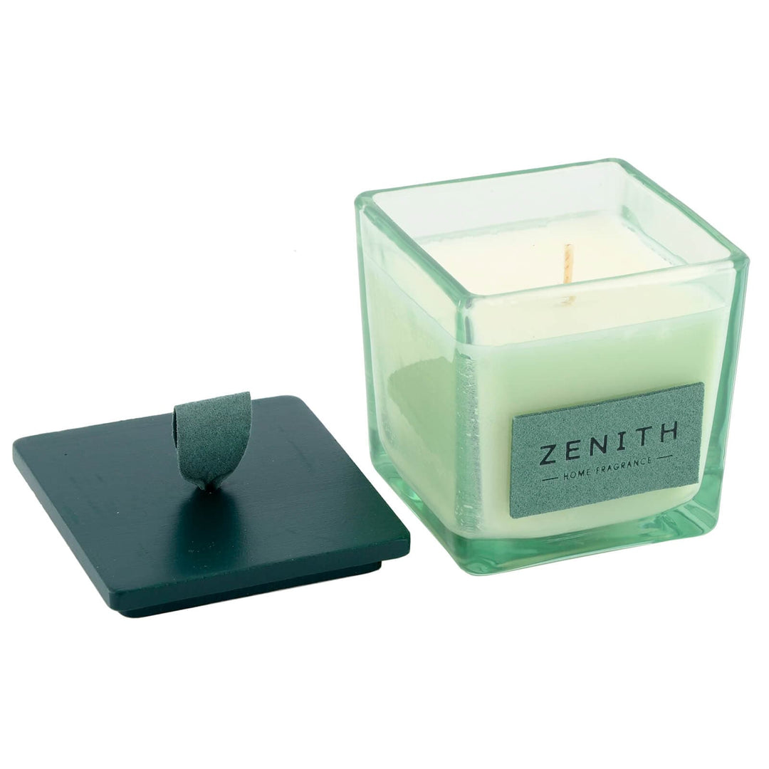 Green candle in a glass container with a lid on a white background
