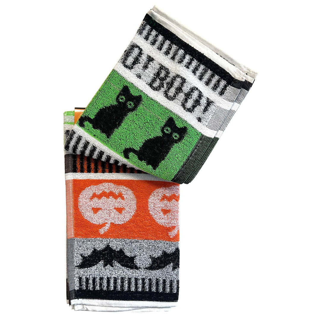Two folded Halloween-themed towels stacked on a white background. The top towel has a green section with two black cats and the words &