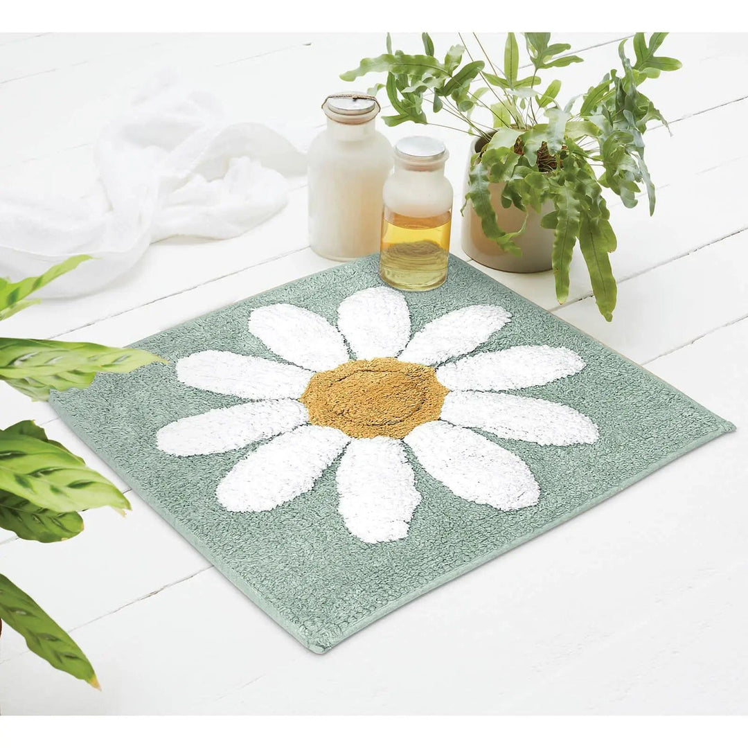 Teal colour daisy pattern square shower mat on a wooden floor with plants and bath oils