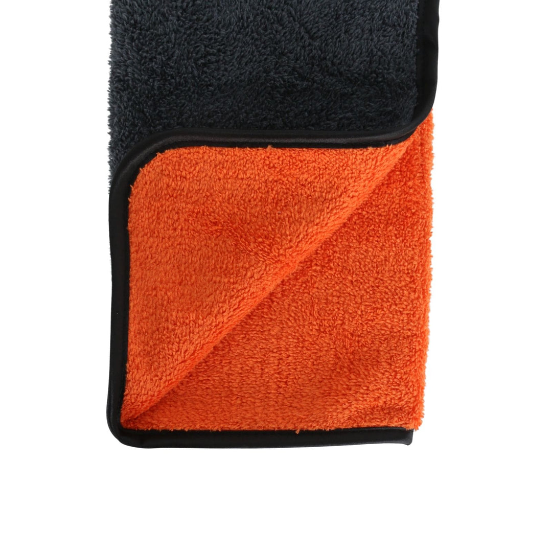 close up of microfibre car buffing towel with grey and orange material and silky black edge piping