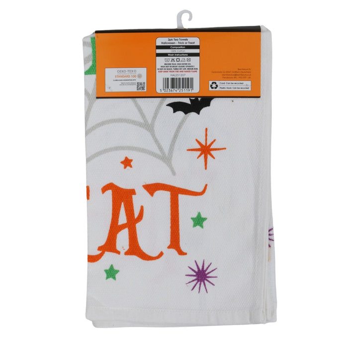 A white Halloween-themed kitchen towel decorated with orange and green stars, a purple starburst, and a black bat. The towel is packaged with an orange retail header card on a white background.