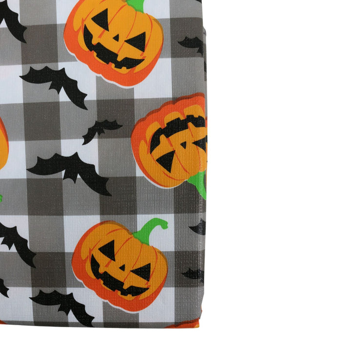 A close-up of tablecover swatch featuring a Halloween buffalo plaid pattern in gray, white, and black, decorated with orange jack-o&