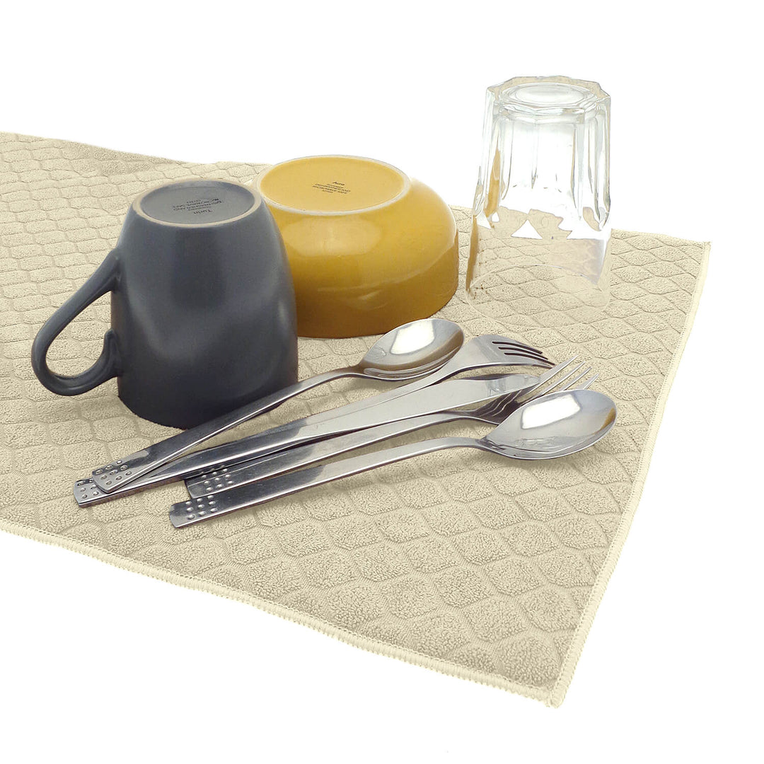 Cutlery drinking glass mug and bowl on a beige colour dish drying mat