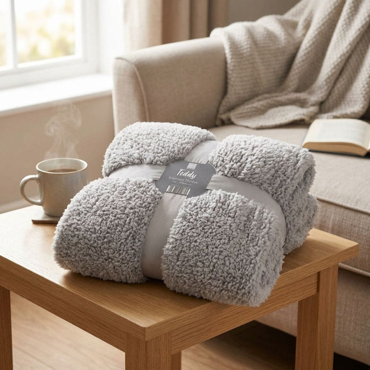 teddy fleece blanket throw on wooden table beside cup of tea with waffle blanket and book in background