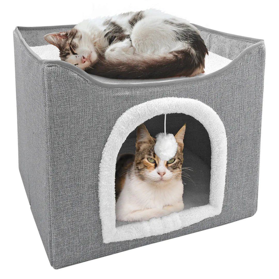 Grey and white cat house with cat sitting inside and another cat curled up on the top pad