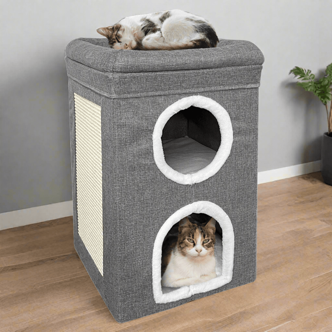 grey and white two story cat house with cat sleeping on top and cat inside bottom story with scratching board to the side