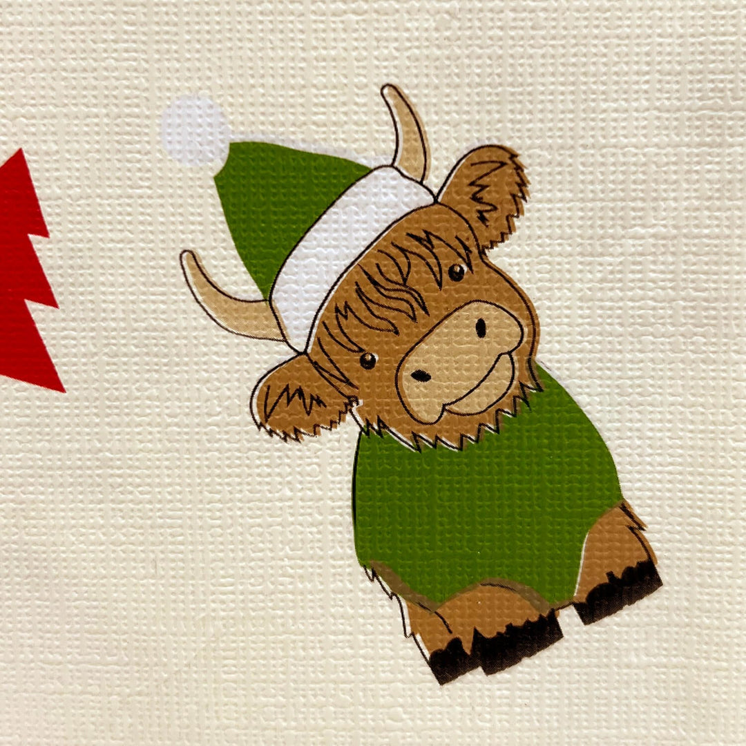 Close up detail of a Highland cow with green and white Christmas hat on cream background
