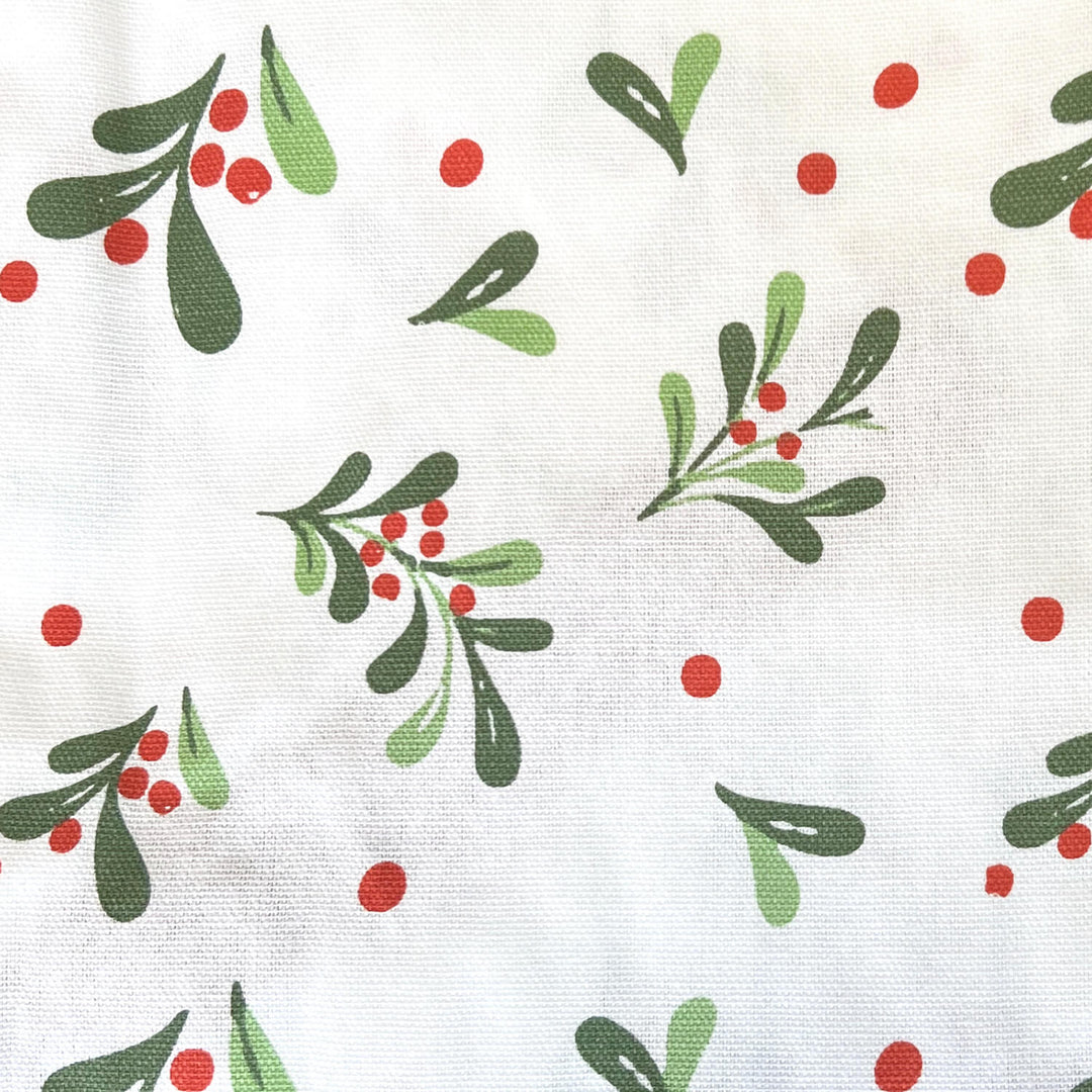Cose up of mistletoe leaves and red berries on white fabric
