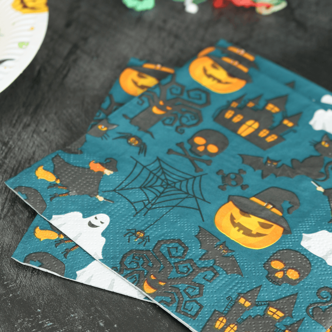 haunted house & grinning pumpkin napkins on a halloween table with party streamers in the background