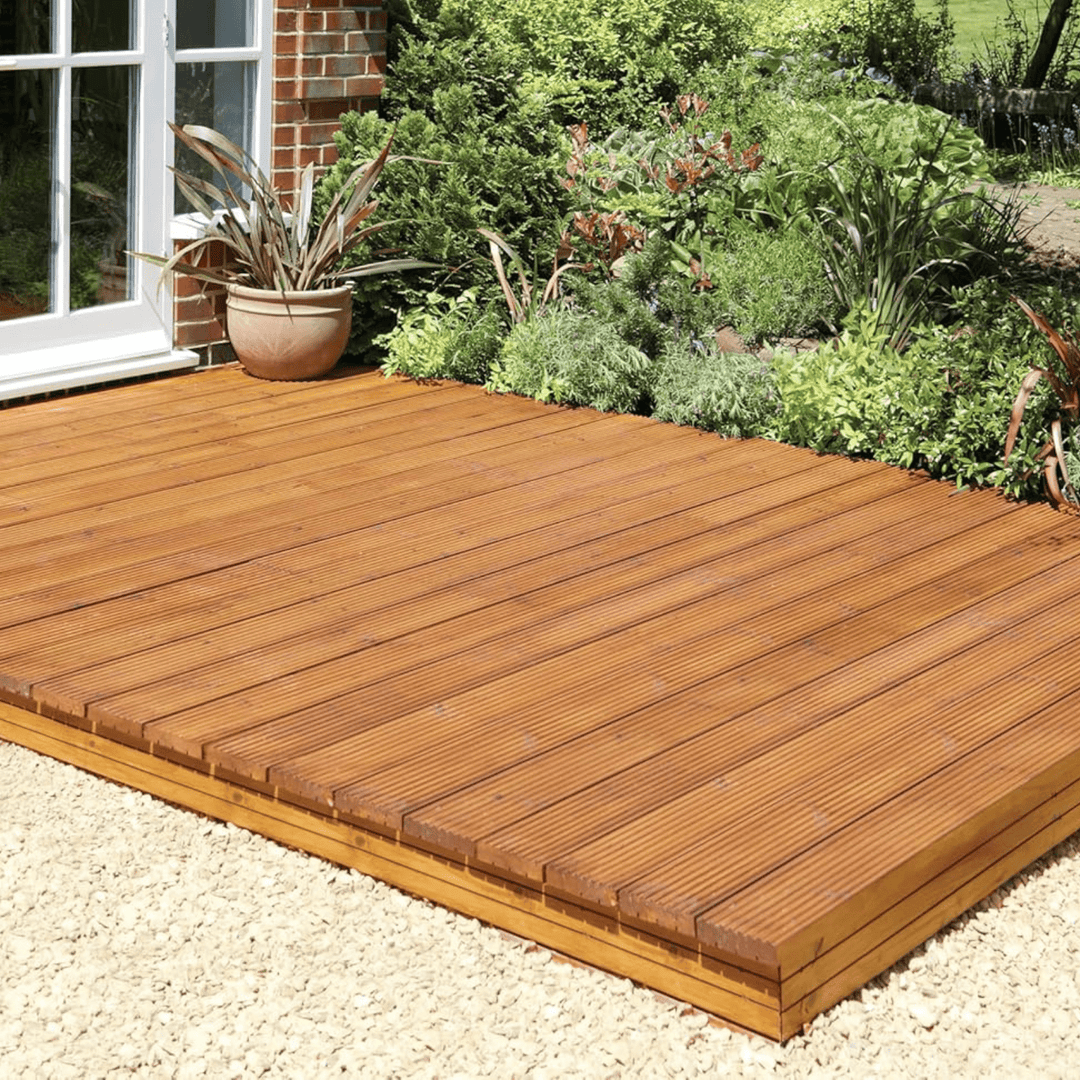 Wooden deck in a garden setting with plants and a window.
