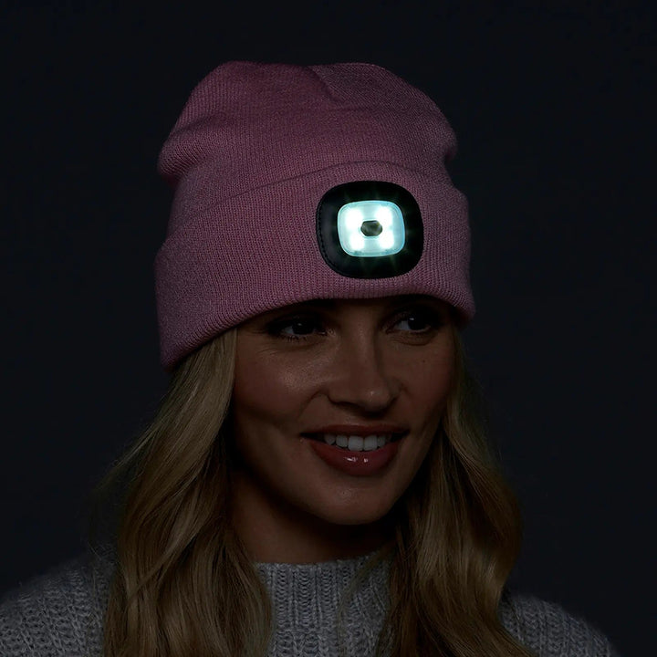 Woman wearing a pink beanie hat in the dark with the integral LED light shining