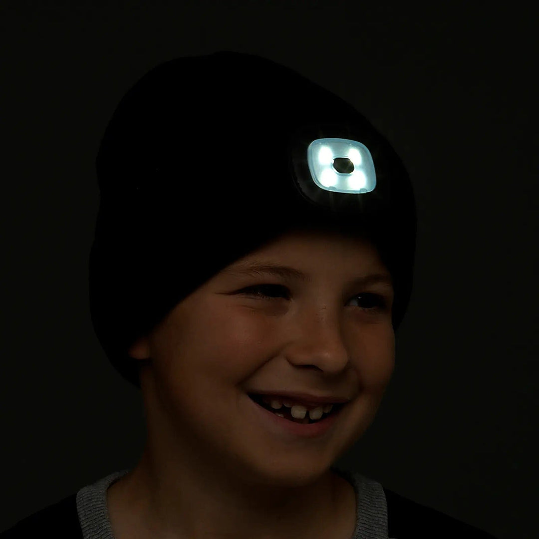 Boy with a black beanie hat in the dark with LED light shining from the front