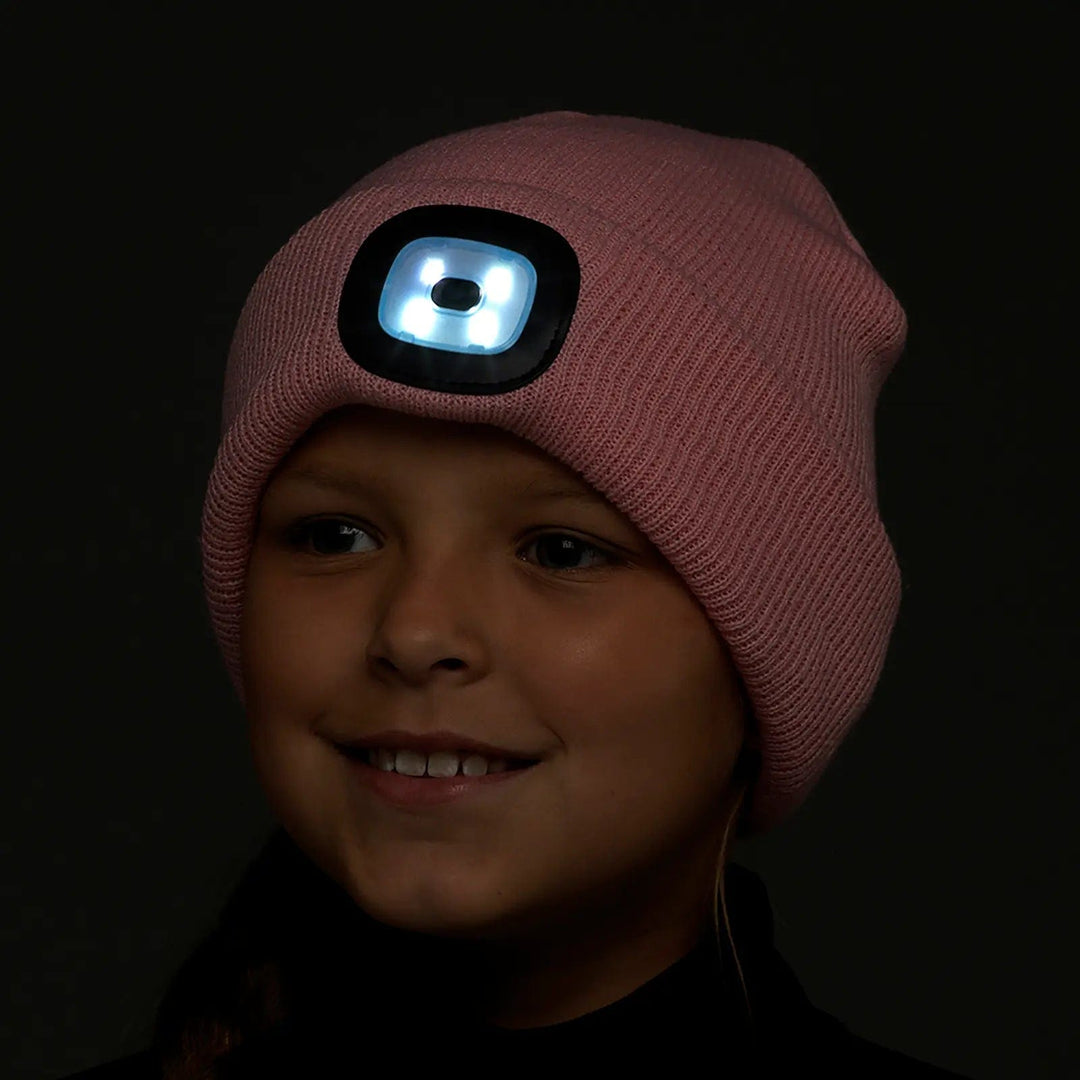 Girl with a pink beanie hat in the dark with LED light shining from the front