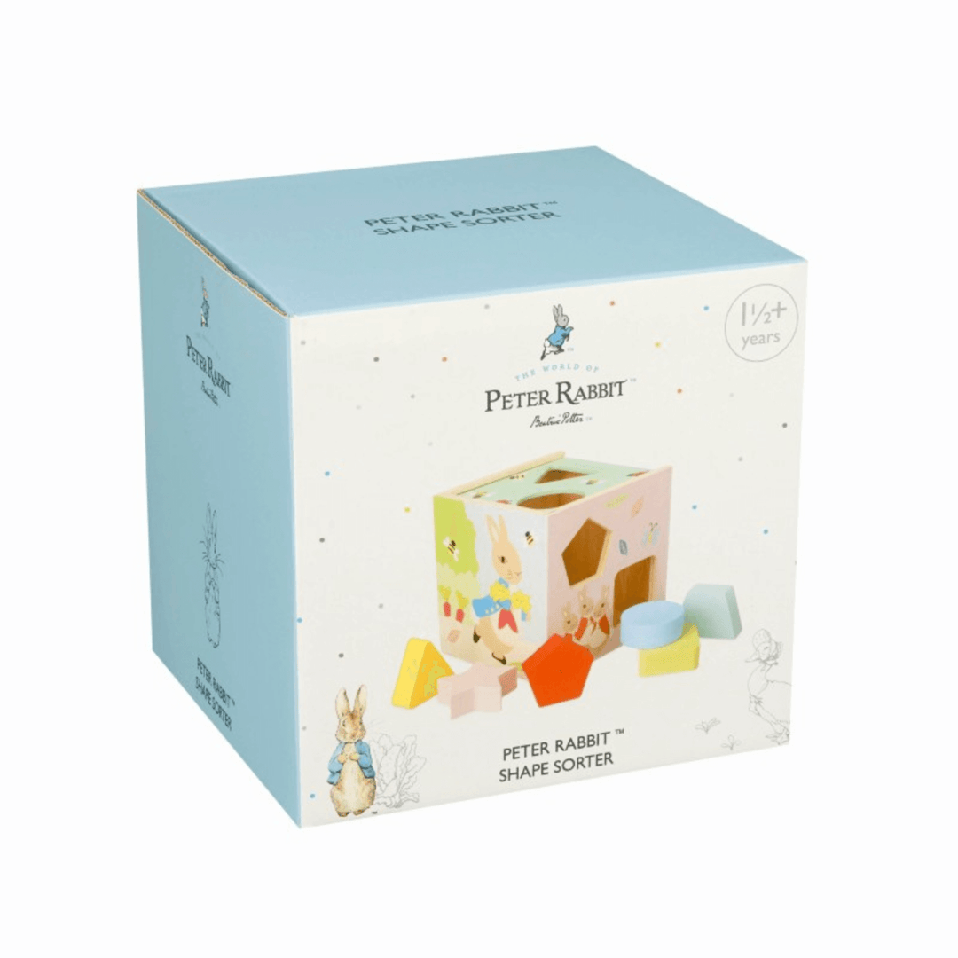 front view of peter rabbit shape sorter toy packaging feature blue cardboard box lid and side, with pastel coloured polka dot pattern all over and image of included shape sorter toy