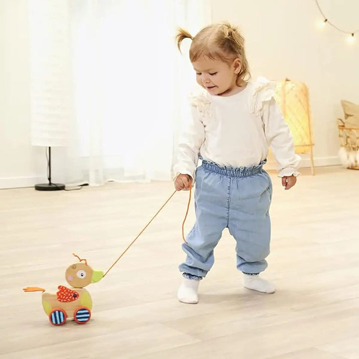 Child playing with a pull along wooden duck toy on a string