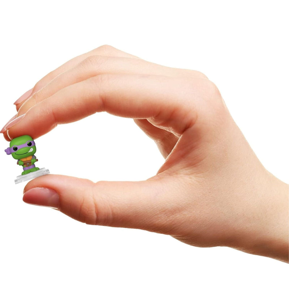 Hand holding a small green figurine against a white background