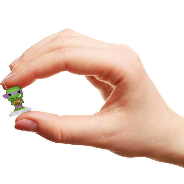 Hand holding a small green figurine against a white background