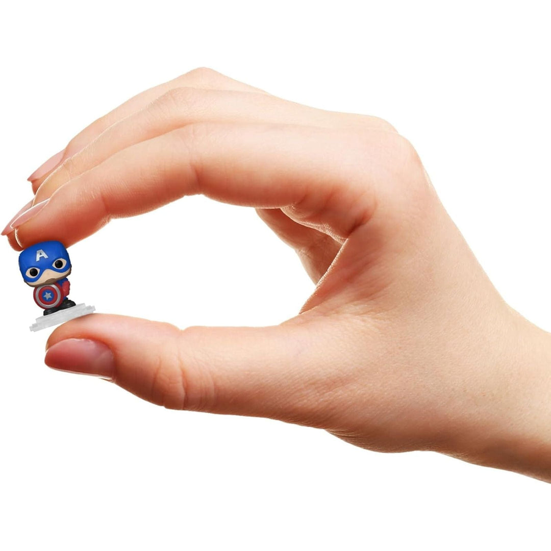Hand holding a small figurine of captain america character on a white background