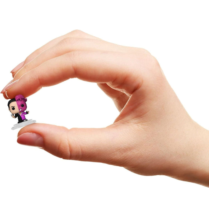Hand holding a small two-face DC figurine against a white background