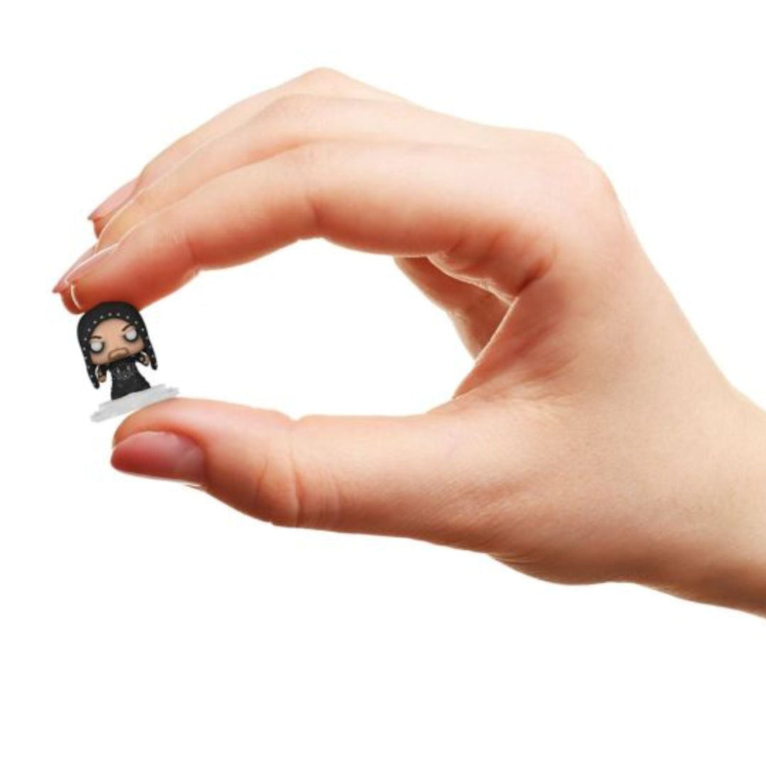 Hand holding a small WWE undertaker figurine against a white background