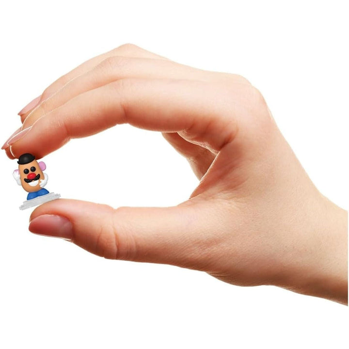 Hand holding a small mr potatohead figurine of a character with a white background