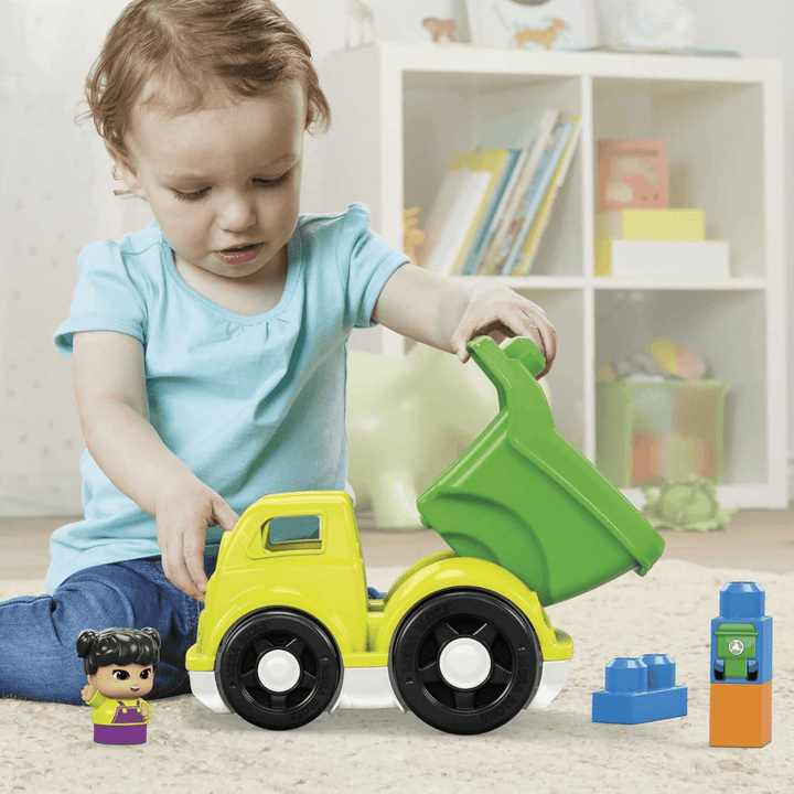 little toddler girl plays with raphy recycling truck, lifting up carriage at back in bedroom with book shelves in background