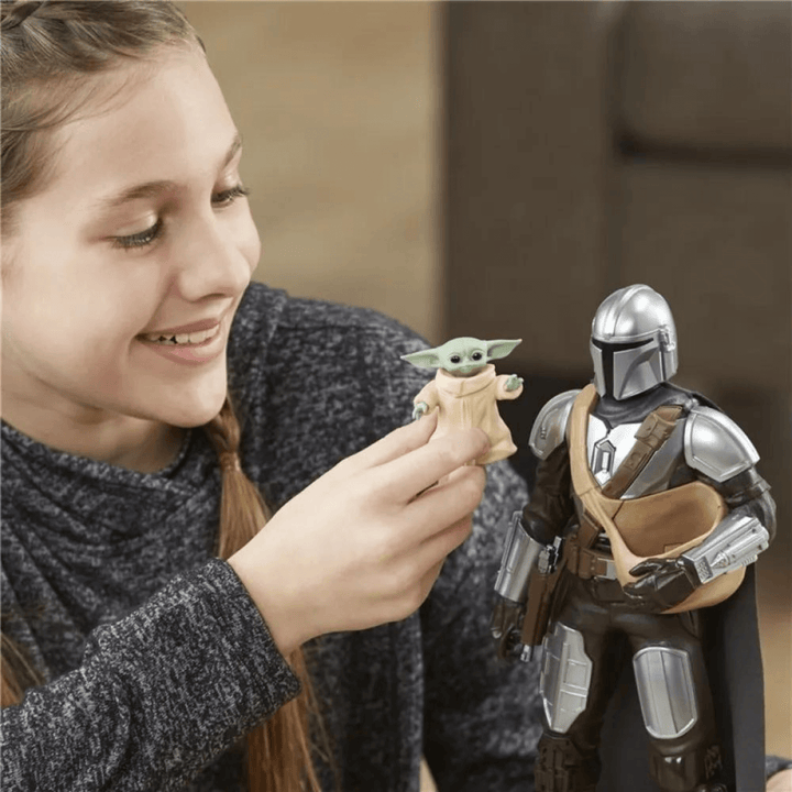 young girl smiles as she plays with mini grogu and the mandalorian action figure toy set.