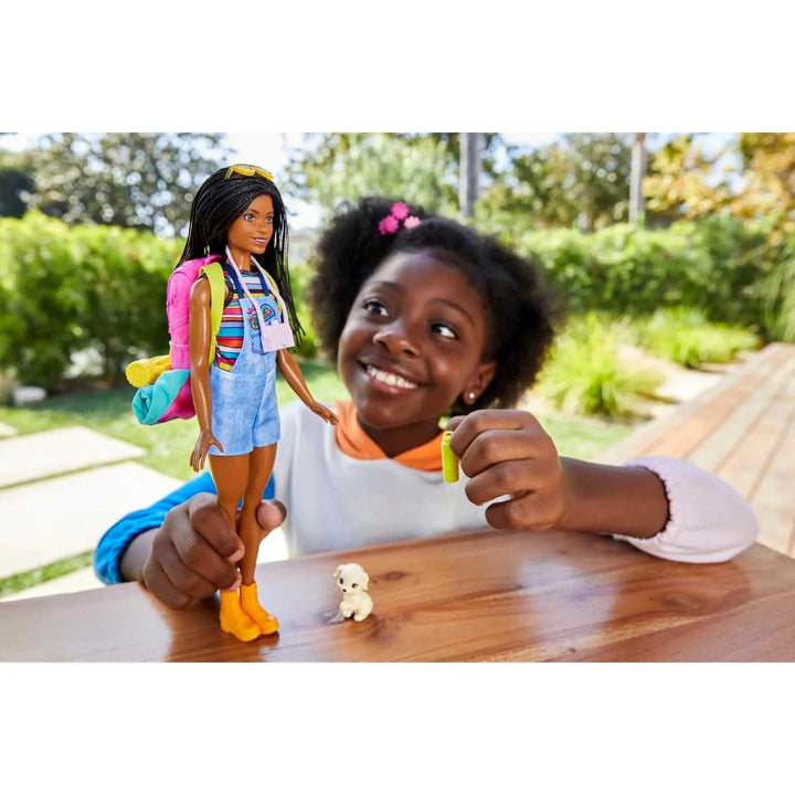 Child playing with camping Barbie doll and white puppy