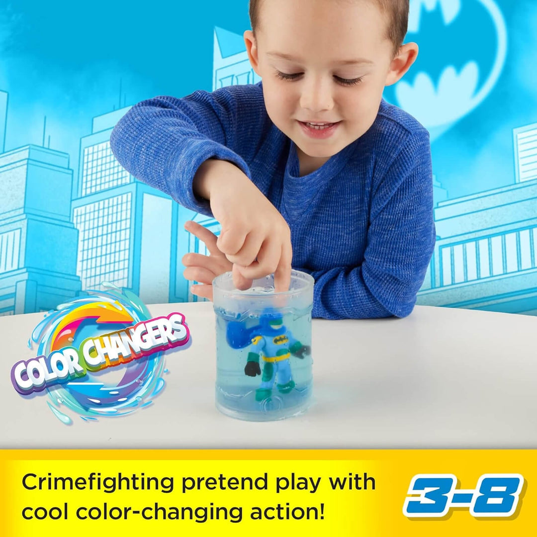 Boy dunking a Batman figure in a canister of water to watch it change colour