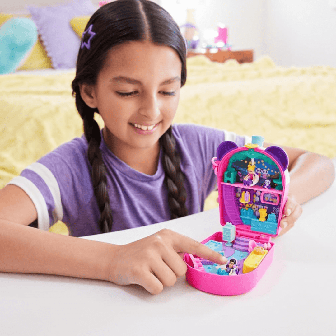 little girls smiles in he bedroom as she plays with her panda bubble tea playset with a micro doll wearing headphone accessories sitting in chair