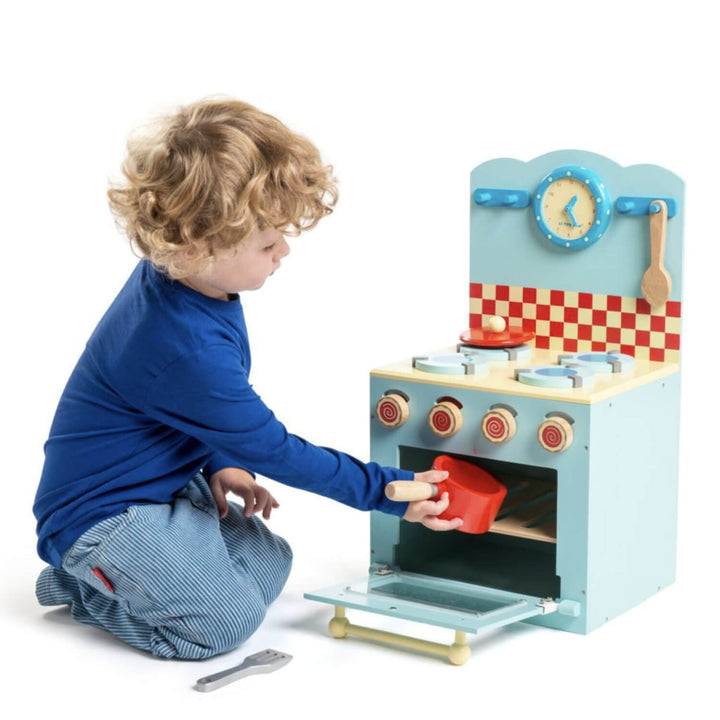 Child playing with a toy kitchen set on a white background