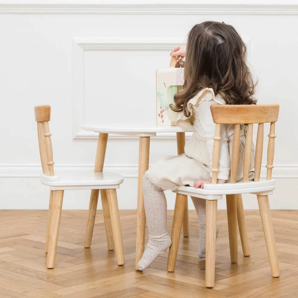 Child sitting on a wooden chair at a white table