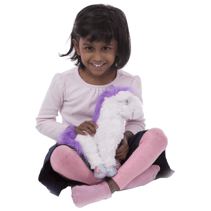 little girl sits misty unicorn in her lap and smiles