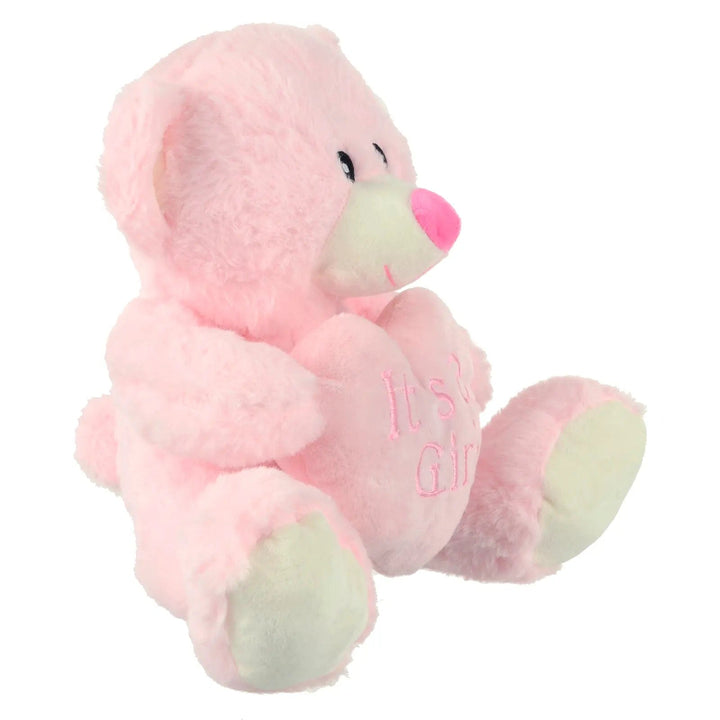 Side view of baby pink teddy bear holding a pink heart