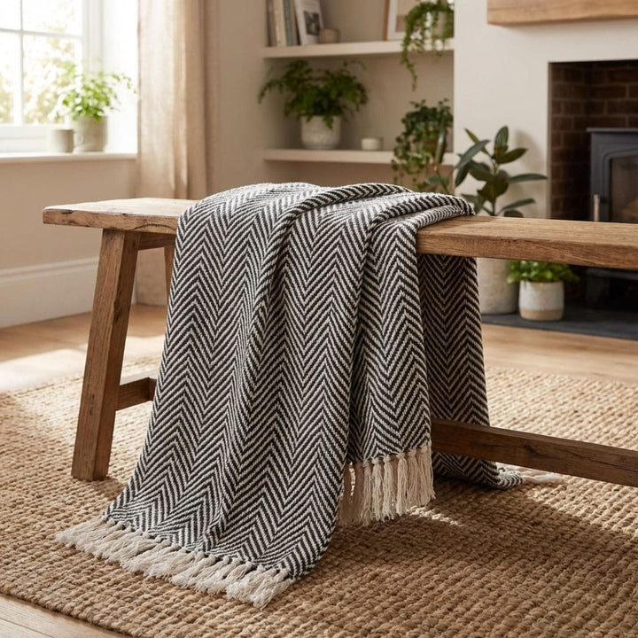 blanket draped over wooden bench in living room with shelves and plants in background