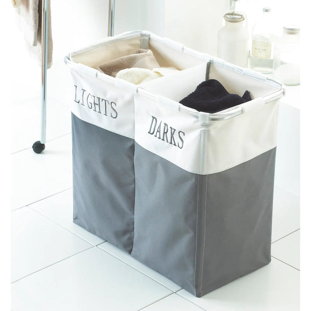 Grey and white laundry basket with 2 compartments printed with Lights and Darks, on a white tiled floor