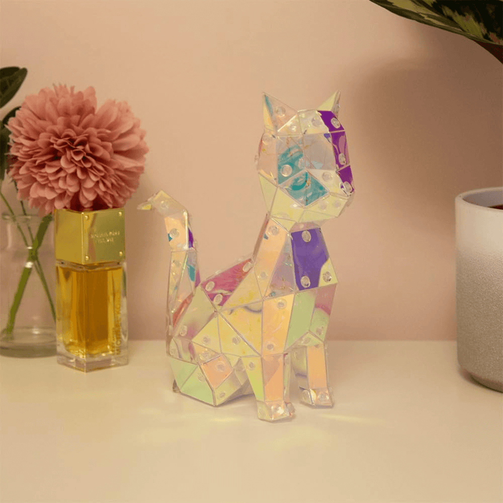 cat night light switched off sitting on vanity table beside plant pot and vase with pink peony flower