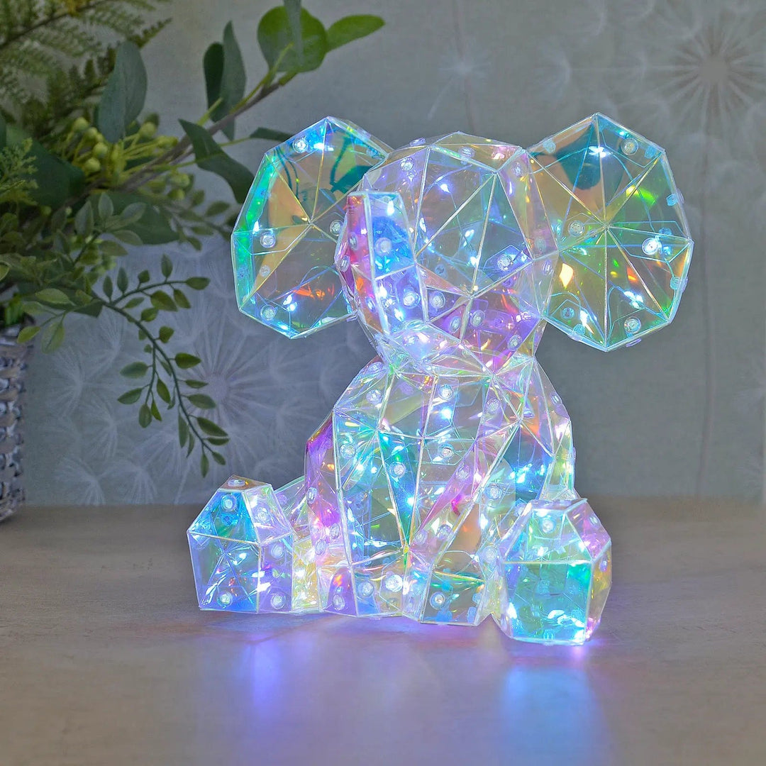 Elephant shape Starlightz light with coloured LEDs lit on a table with foliage plant