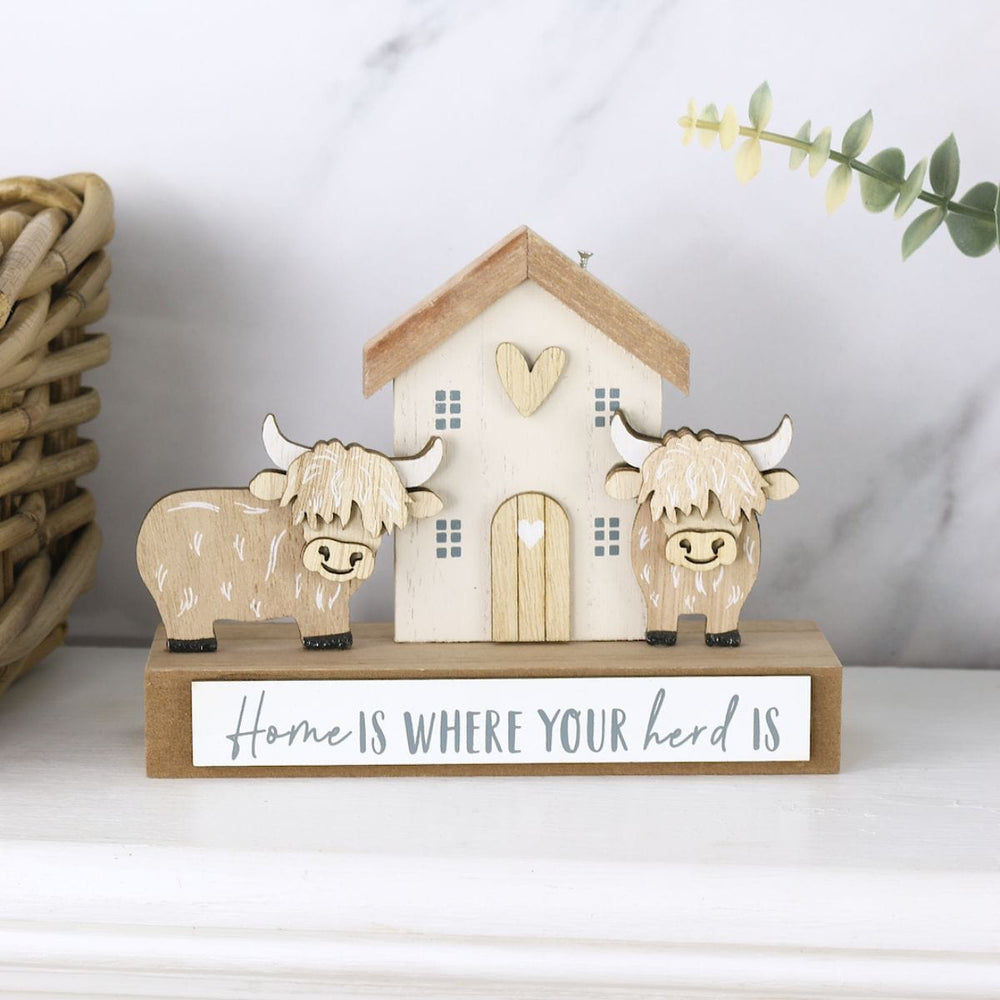 Decorative wooden house with two cows and a sign on a marble surface