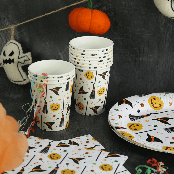 white pumpkin & witch paper plates, napkins and cups on a halloween table with pumpkin garland in the background