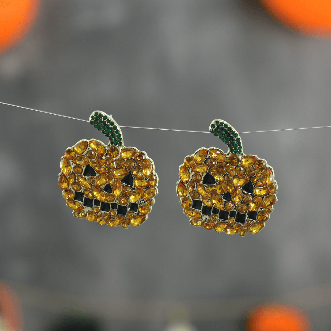 pumpkin stud earrings hanging on black and orange background